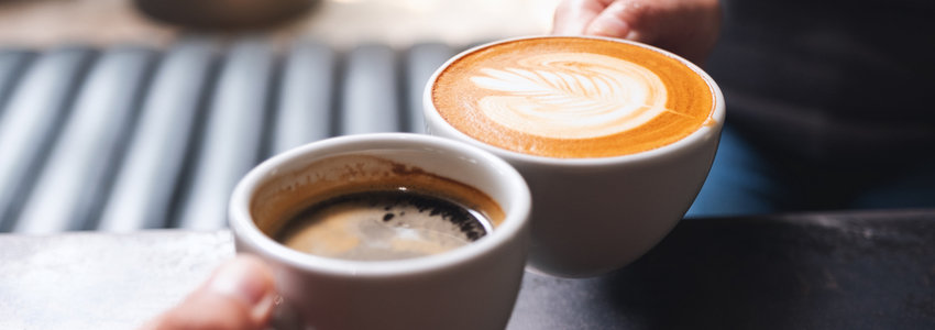 Close up of two people holding coffee cups in a cafe
