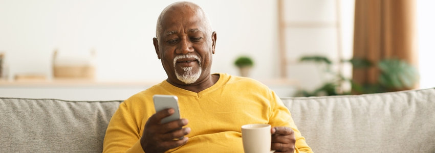 A man enjoying a cup of coffee and looking at his phone.