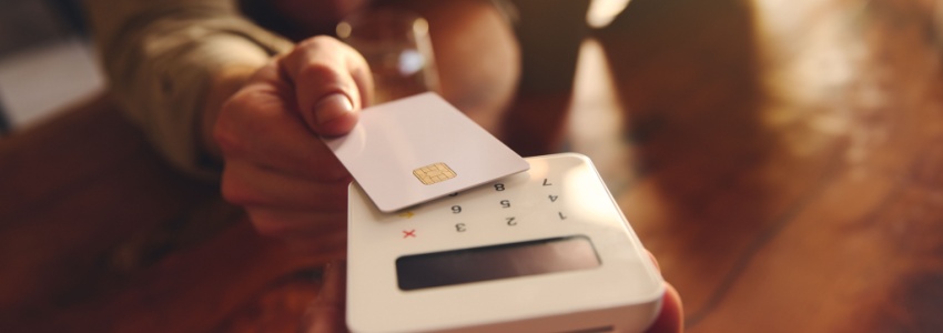 A person using their debit card to pay in a café.