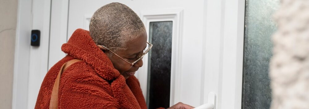 A woman unlocking a front door.